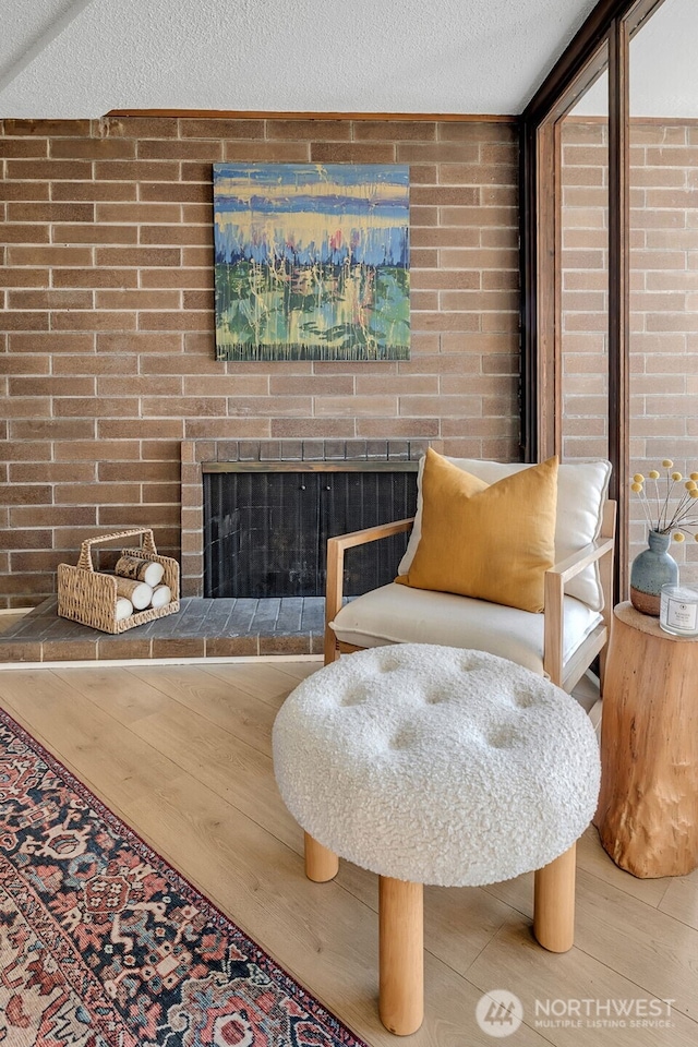 9500 Rainier Ave S Unit 303, Seattle, WA 98118 - living area with wood finished floors, a textured ceiling, a fireplace, and brick wall