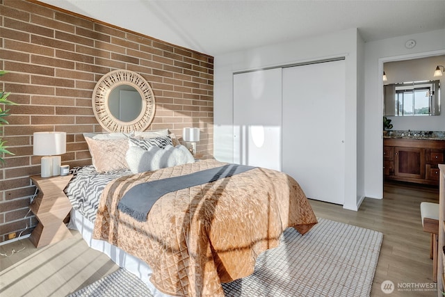 9500 Rainier Ave S Unit 303, Seattle, WA 98118 - bedroom featuring wood finished floors, a closet, and brick wall