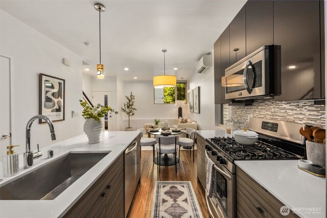 721 26th Ave S Unit B, Seattle, WA 98144 - kitchen with appliances with stainless steel finishes, wood finished floors, backsplash, a wall unit AC, and pendant lighting