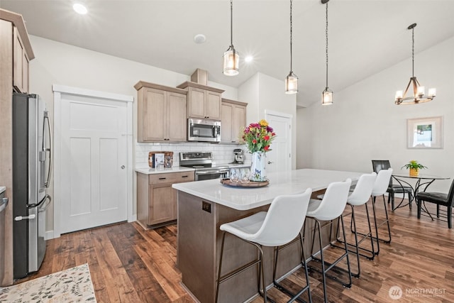 918 N M Loop Dr SW, Quincy, WA 98848 - kitchen with appliances with stainless steel finishes, dark wood-style floors, decorative backsplash, vaulted ceiling, and a breakfast bar
