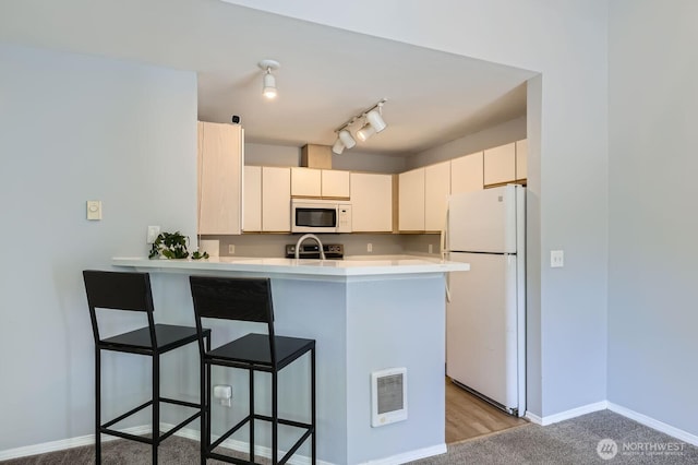 9210 Market Pl Unit F202, Lake Stevens, WA 98258 - kitchen with white appliances, a peninsula, a breakfast bar area, light countertops, and rail lighting