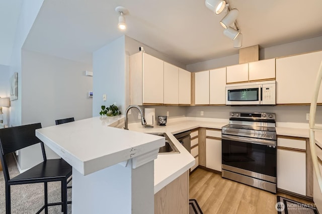 9210 Market Pl Unit F202, Lake Stevens, WA 98258 - kitchen with white microwave, electric stove, a peninsula, a kitchen breakfast bar, and light countertops