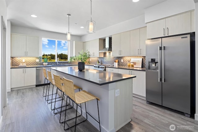 17905 35th Ave SE Unit C3, Bothell, WA 98012 - kitchen with high end appliances, wall chimney exhaust hood, dark countertops, a breakfast bar, and light wood-type flooring