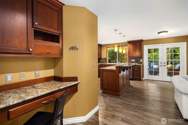 15214 102nd Ave NE, Bothell, WA 98011 - kitchen with french doors, dark wood-type flooring, a kitchen bar, tasteful backsplash, and light stone countertops