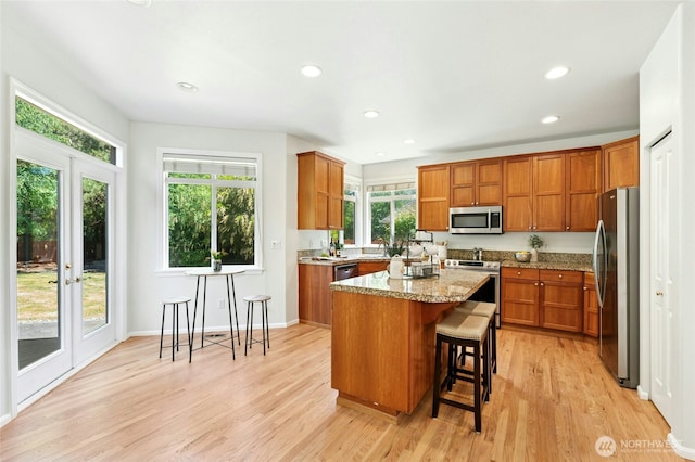 3303 174th Pl SE, Bothell, WA 98012 - kitchen with stainless steel appliances, brown cabinets, a kitchen island, light wood-style flooring, and plenty of natural light