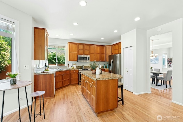 3303 174th Pl SE, Bothell, WA 98012 - kitchen with stainless steel appliances, light wood finished floors, brown cabinetry, a kitchen island, and recessed lighting