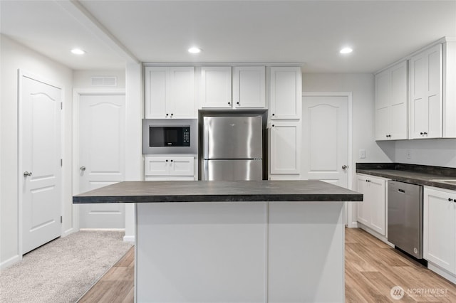 25405 36th Ave E, Spanaway, WA 98387 - kitchen featuring stainless steel appliances, dark countertops, light wood-style floors, white cabinets, and recessed lighting