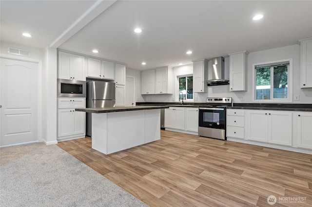 25405 36th Ave E, Spanaway, WA 98387 - kitchen featuring appliances with stainless steel finishes, wall chimney range hood, dark countertops, light wood-style floors, and white cabinets