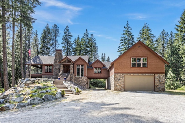 16060 Telemark Ln, Leavenworth, WA 98826 - view of front of home featuring stone siding, stairs, a garage, gravel driveway, and a chimney