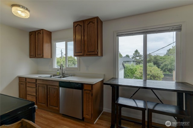 4637 N Visscher St, Tacoma, WA 98407 - kitchen featuring stainless steel dishwasher, light wood-style floors, light countertops, and brown cabinets