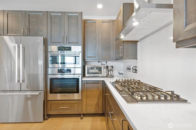 4907 Main St Unit 207, Tacoma, WA 98407 - kitchen with stainless steel appliances, wall chimney range hood, light countertops, light wood finished floors, and recessed lighting