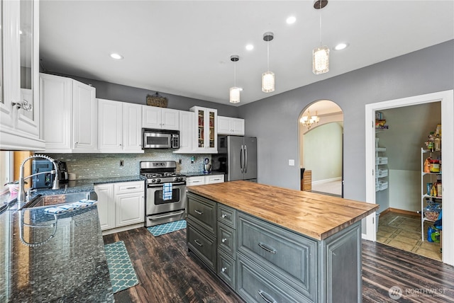 20523 193rd Avenue Ct E, Orting, WA 98360 - kitchen with appliances with stainless steel finishes, white cabinetry, butcher block countertops, arched walkways, and glass insert cabinets