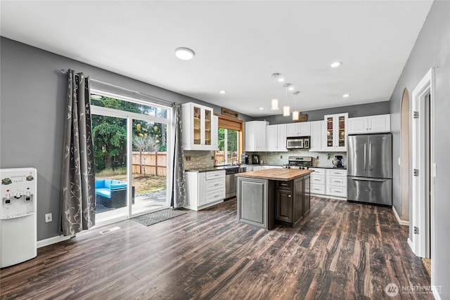 20523 193rd Avenue Ct E, Orting, WA 98360 - kitchen featuring appliances with stainless steel finishes, butcher block counters, dark wood finished floors, tasteful backsplash, and a kitchen island