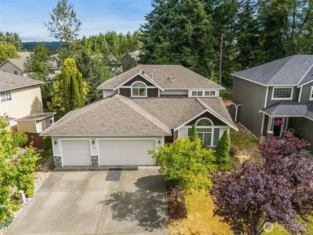 20523 193rd Avenue Ct E, Orting, WA 98360 - view of front of home with an attached garage, concrete driveway, a shingled roof, and stone siding