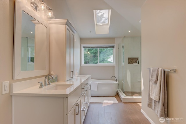 18915 SE 284th Ct, Kent, WA 98042 - bathroom with double vanity, a freestanding bath, a stall shower, a skylight, and wood finished floors