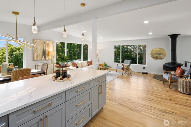 12569 37th Ave NE, Seattle, WA 98125 - kitchen featuring gray cabinets, open floor plan, a wood stove, light wood-style floors, and hanging light fixtures
