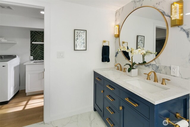 12569 37th Ave NE, Seattle, WA 98125 - bathroom featuring washer / dryer, double vanity, and marble look tiles