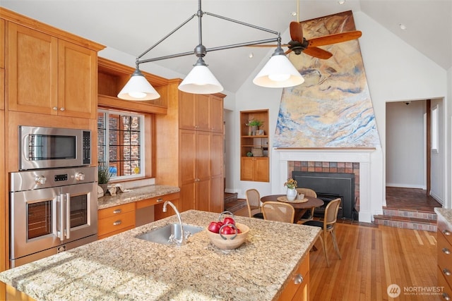 3851 Cliffside Dr, Bellingham, WA 98225 - kitchen featuring stainless steel appliances, ceiling fan, light wood-style floors, an island with sink, and high vaulted ceiling