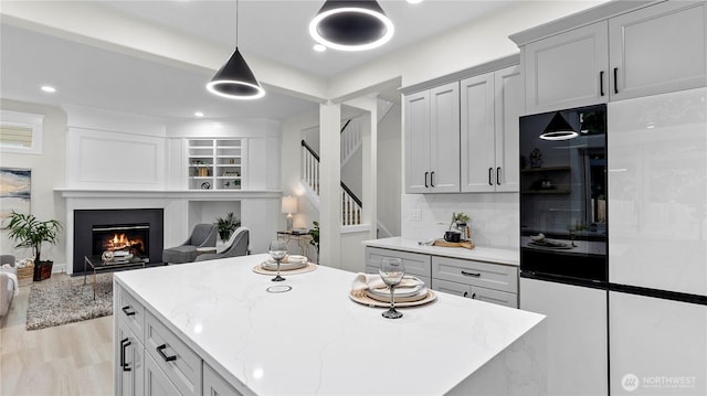 11832 158th Ave NE, Redmond, WA 98052 - kitchen featuring refrigerator, open floor plan, light stone counters, a lit fireplace, and a kitchen island