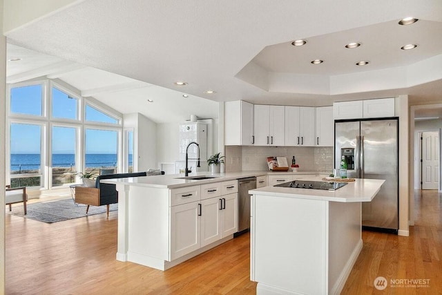 12 Jamestown Beach Ln, Sequim, WA 98382 - kitchen featuring stainless steel appliances, a peninsula, light wood-style flooring, light countertops, and white cabinetry