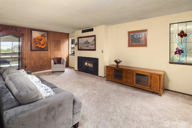 335 3rd Ave S Unit 203, Edmonds, WA 98020 - carpeted living room featuring a textured ceiling, wooden walls, and a warm lit fireplace
