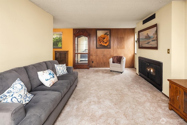 335 3rd Ave S Unit 203, Edmonds, WA 98020 - living area featuring a warm lit fireplace, light colored carpet, a textured ceiling, and wood walls