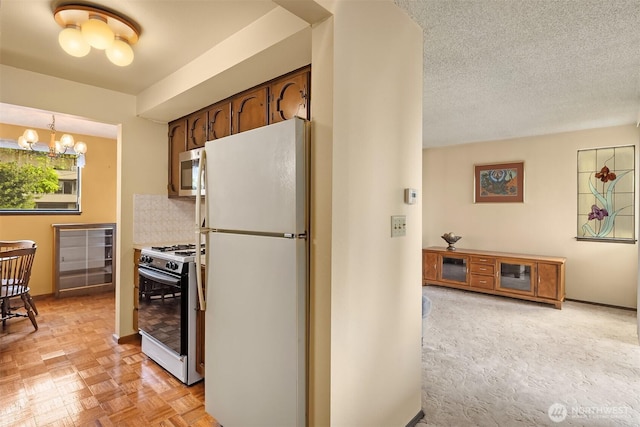 335 3rd Ave S Unit 203, Edmonds, WA 98020 - kitchen with freestanding refrigerator, range with gas cooktop, a chandelier, and tasteful backsplash