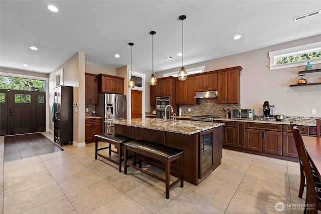 1132 121st St E, Tacoma, WA 98445 - kitchen with under cabinet range hood, stainless steel appliances, plenty of natural light, tasteful backsplash, and recessed lighting