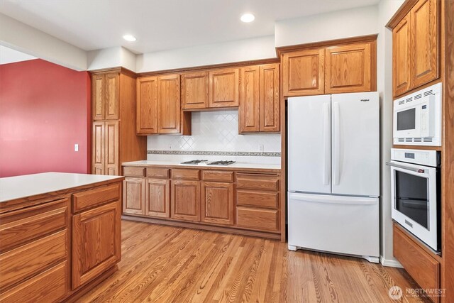 3819 Ridge Ct, Mount Vernon, WA 98274 - kitchen with white appliances, brown cabinetry, light wood-type flooring, light countertops, and tasteful backsplash