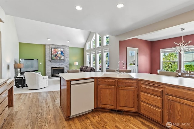 3819 Ridge Ct, Mount Vernon, WA 98274 - kitchen with dishwasher, a large fireplace, light countertops, vaulted ceiling, and light wood-style flooring