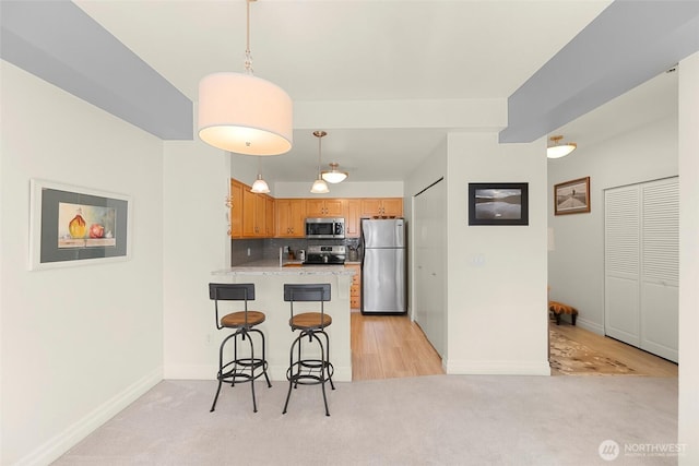 910 Harris Ave Unit 304, Bellingham, WA 98225 - kitchen featuring appliances with stainless steel finishes, light colored carpet, a peninsula, a kitchen bar, and tasteful backsplash
