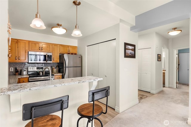 910 Harris Ave Unit 304, Bellingham, WA 98225 - kitchen featuring stainless steel appliances, a peninsula, a breakfast bar, decorative backsplash, and decorative light fixtures