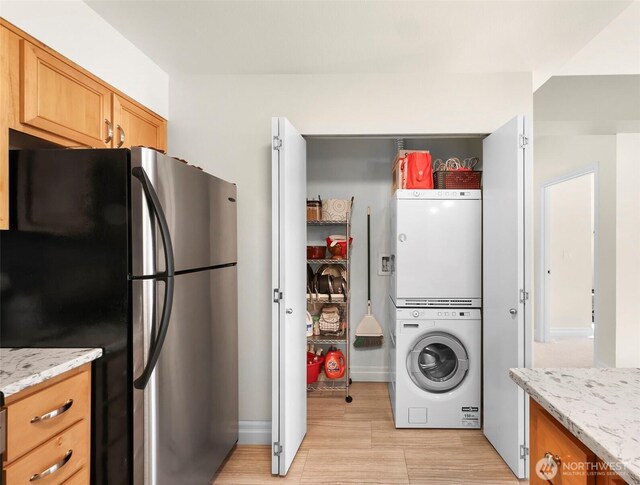 910 Harris Ave Unit 304, Bellingham, WA 98225 - kitchen with freestanding refrigerator, stacked washer / drying machine, light stone counters, and fridge