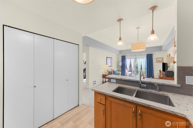 910 Harris Ave Unit 304, Bellingham, WA 98225 - kitchen with pendant lighting, light stone counters, brown cabinetry, open floor plan, and decorative backsplash