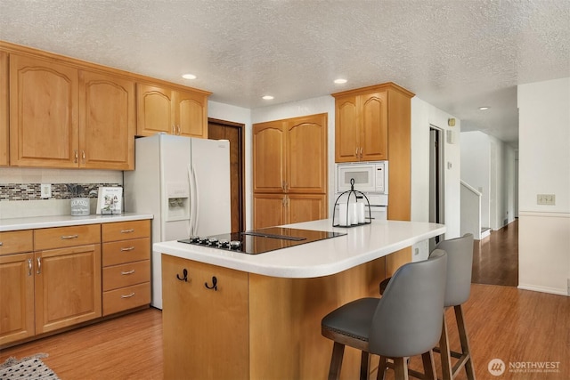 9119 185th Pl SW, Edmonds, WA 98026 - kitchen featuring light wood-type flooring, a breakfast bar, a kitchen island, decorative backsplash, and recessed lighting