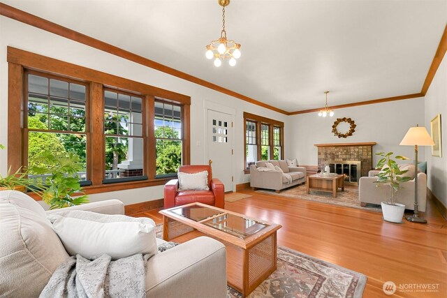 1800 Dakin St, Bellingham, WA 98229 - living room featuring light wood-style flooring, a chandelier, crown molding, and a glass covered fireplace