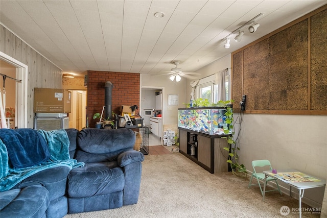229 N Garfield Ave, Wenatchee, WA 98801 - living area with a wood stove, carpet flooring, a ceiling fan, and wooden walls