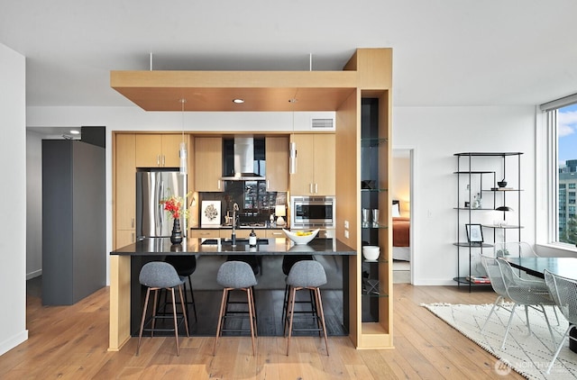 1321 Seneca St Unit 1001, Seattle, WA 98101 - kitchen with appliances with stainless steel finishes, dark countertops, wall chimney exhaust hood, and light wood-type flooring