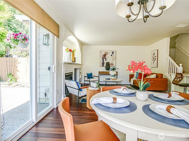 18808 19th Dr SE, Bothell, WA 98012 - dining area featuring wood finished floors, a chandelier, a glass covered fireplace, and stairs