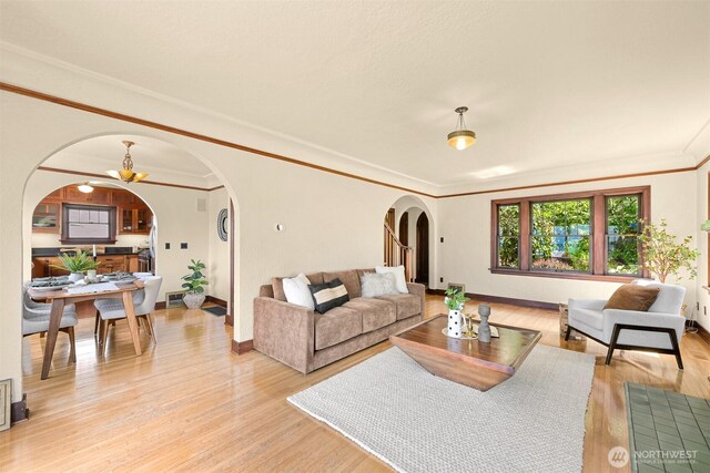 251 N Garden St, Bellingham, WA 98225 - living room featuring arched walkways, light wood-style floors, ornamental molding, and a chandelier