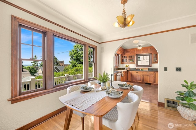 251 N Garden St, Bellingham, WA 98225 - dining room with arched walkways, light wood finished floors, a textured wall, a chandelier, and crown molding