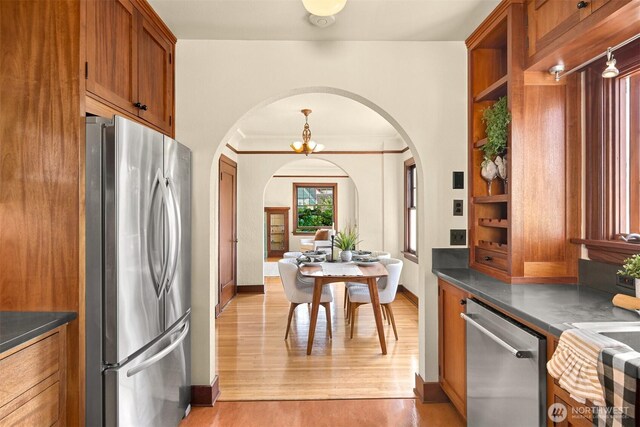 251 N Garden St, Bellingham, WA 98225 - kitchen with appliances with stainless steel finishes, arched walkways, dark countertops, brown cabinets, and light wood-style floors