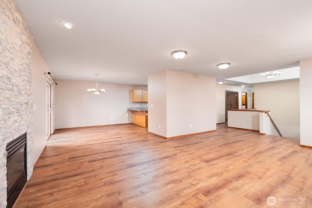 3706 54th St E, Tacoma, WA 98443 - unfurnished living room with a chandelier, a stone fireplace, and light wood-type flooring