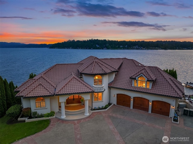 2819 E Lake Sammamish Pkwy NE, Sammamish, WA 98074 - mediterranean / spanish home featuring a tile roof, concrete driveway, stucco siding, and a water view