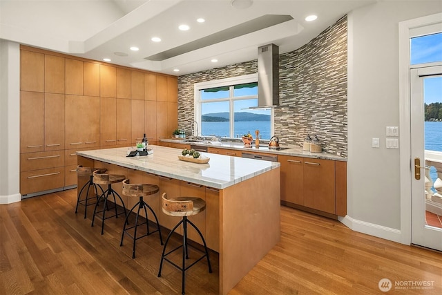2819 E Lake Sammamish Pkwy NE, Sammamish, WA 98074 - kitchen with wall chimney exhaust hood, wood finished floors, a kitchen bar, a kitchen island, and recessed lighting
