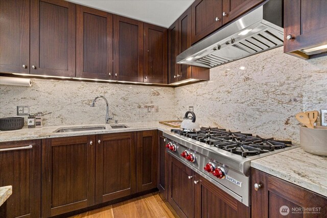 10700 NE 4th St Unit 712, Bellevue, WA 98004 - kitchen with under cabinet range hood, stainless steel gas cooktop, backsplash, light stone countertops, and light wood-type flooring