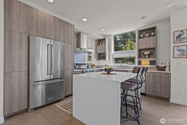 1100 14th Ave, Seattle, WA 98122 - kitchen with appliances with stainless steel finishes, wall chimney range hood, open shelves, a kitchen breakfast bar, and light wood-style flooring