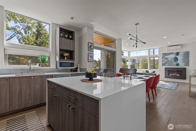 1100 14th Ave, Seattle, WA 98122 - kitchen featuring a wall mounted air conditioner, light countertops, stainless steel microwave, a kitchen island, and a glass covered fireplace