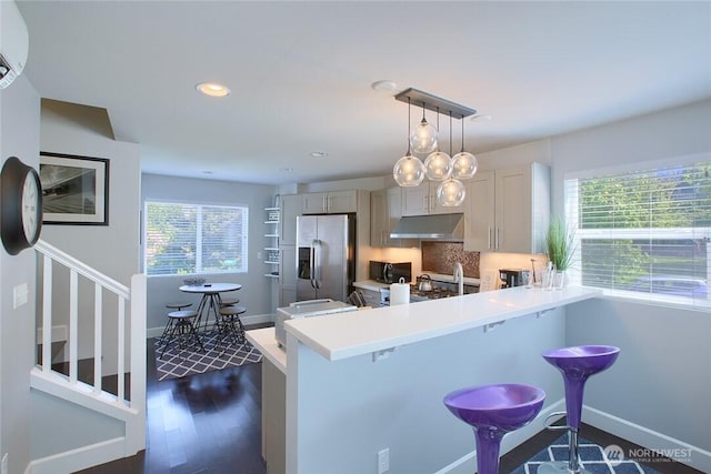 2067 Gilman Dr W, Seattle, WA 98119 - kitchen featuring stainless steel fridge with ice dispenser, under cabinet range hood, a breakfast bar, light countertops, and black microwave