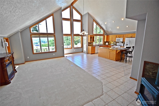 1923 SE Maple Dr, Chehalis, WA 98532 - living room featuring a wood stove, light tile patterned flooring, high vaulted ceiling, a textured ceiling, and a chandelier
